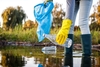 Person sammelt Plastik aus Gewässer