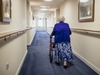Seniorin geht an einem Rollator durch den Flur in einem Pflegeheim