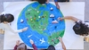 eine Gruppe von Kindern, die einen Globus mit Tieren, Fischen und Booten malen