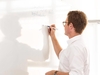 Mann schreibt an der Wand auf ein Whiteboard