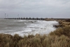 Dünen, wildes Meer mit hohen Wellen und im Hintergrund eine geschlossene Sturmsperre